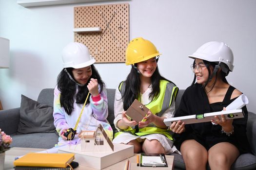 Three asian girls in safety helmet pretend to be engineer.