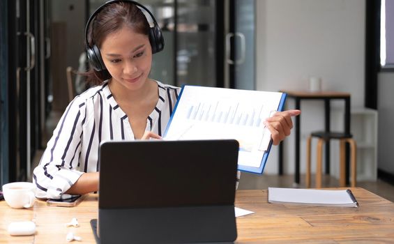 Happy asian woman young wearing headset, communicating with client via video computer call..