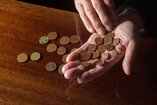 Wrinkled hands of elderly woman counting coins. Close up.