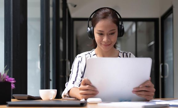 Happy asian woman young wearing headset, communicating with client via video computer call..