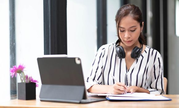 Happy asian woman young wearing headset, communicating with client via video computer call..