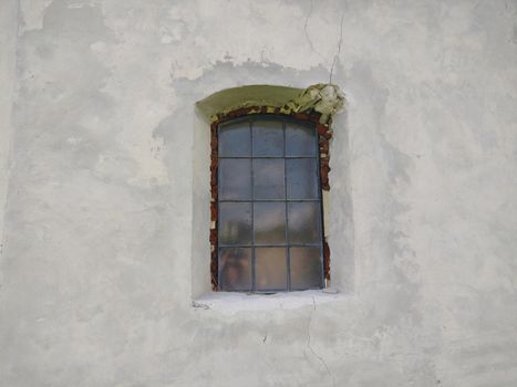 An old window in the gray wall of an old church.