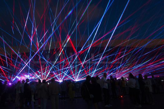 Laser lights and people silhouettes at city square. Celebrating city anniversary.