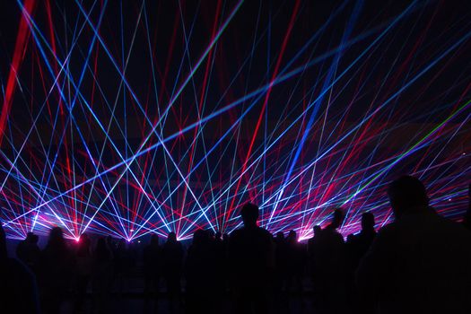 Laser lights and people silhouettes at city square. Celebrating city anniversary.