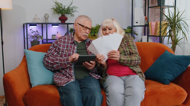 Stressed old senior family couple grandparents man woman discuss unpaid bank debt holding bills, doing paperwork, planning budget, discuss finances calculate mortgage payments, paper at home
