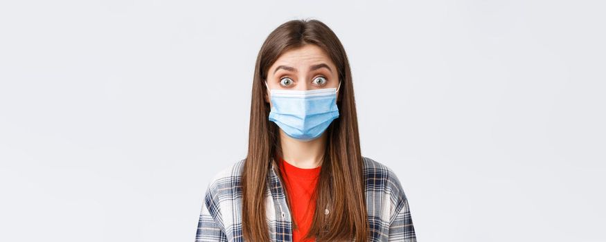 Coronavirus outbreak, leisure on quarantine, social distancing and emotions concept. Close-up of intrigued, surprised woman hear interesting news, wear medical mask, widen eyes.
