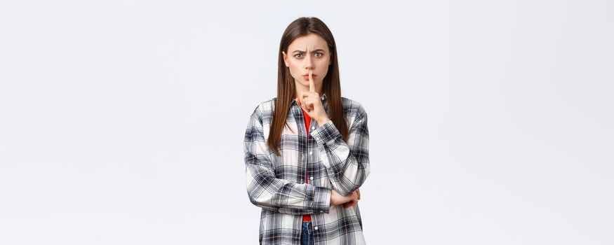 Lifestyle, different emotions, leisure activities concept. Angry serious-looking young woman tell shut up, keep quiet. Girl shushing at you with index finger pressed to lips, frowning disappointed.