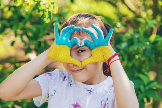 A child with the flag of Ukraine painted on his hands. Selective focus. Kid.