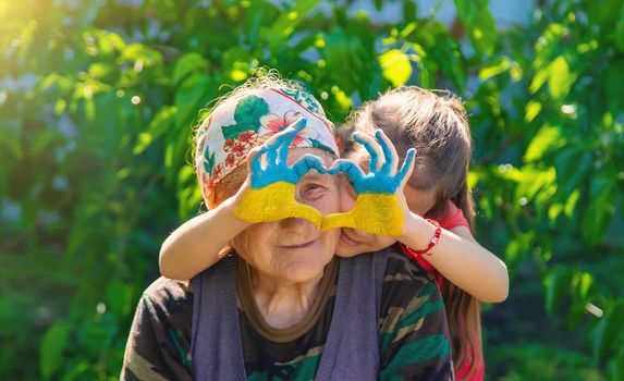 Child and grandmother hand drawn flag of Ukraine. Selective focus. Kid.