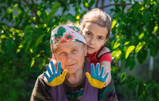 Child and grandmother hand drawn flag of Ukraine. Selective focus. Kid.