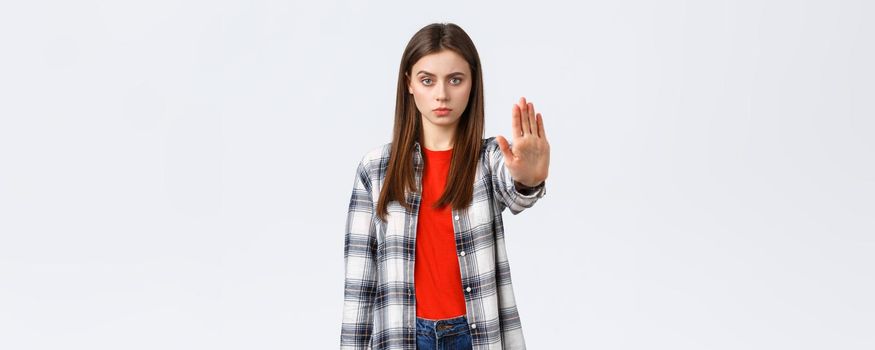 Lifestyle, different emotions, leisure activities concept. Time to stop. Serious young woman in casual outfit, stretch hand forward to prohibit, restrict or forbid something, white background.
