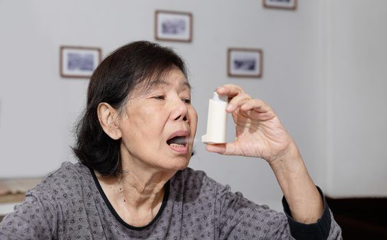 Elderly woman choking and holding an asthma spray