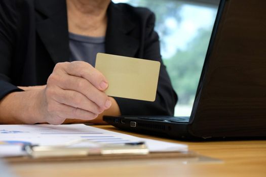 woman holding credit card using computer for online shopping. businesswoman purchase product from internet, make payment on bank website at workplace