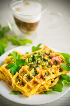 Egg omelet stuffed with greens and sausage fried in the form of waffles, on a wooden table