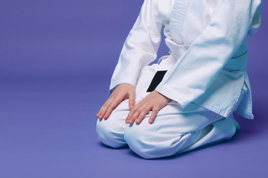 Cropped view of an aikido fighter in a white kimono during the practice of oriental martial arts, isolated over purple background with copy space for advertising text