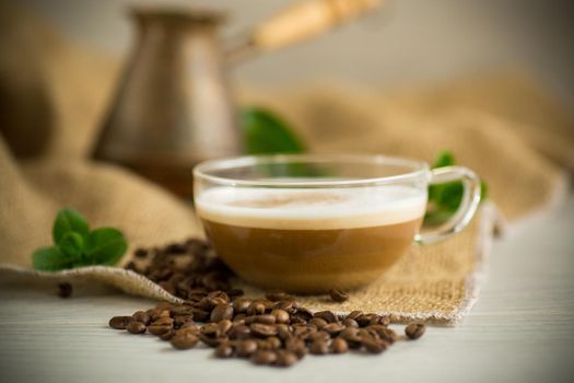 Cup of coffee latte with heart shape and coffee beans on old wooden background