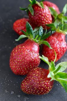 On a black background ripe red strawberry berries close-up.