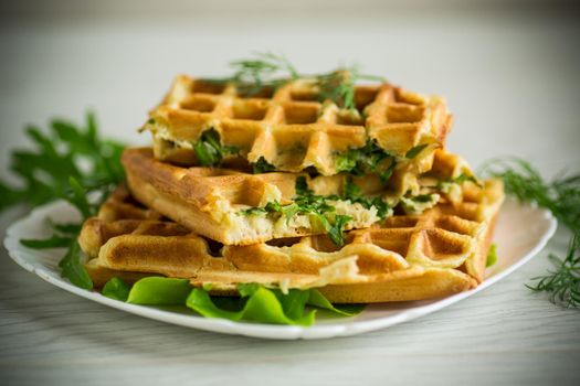 Homemade fried vegetable waffles with herbs inside on a wooden table