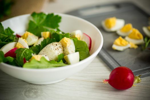 Fresh spring salad with fresh lettuce leaves, radishes, boiled eggs in a bowl on a wooden table