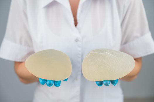 Doctor plastic surgeon demonstrates different breast implants