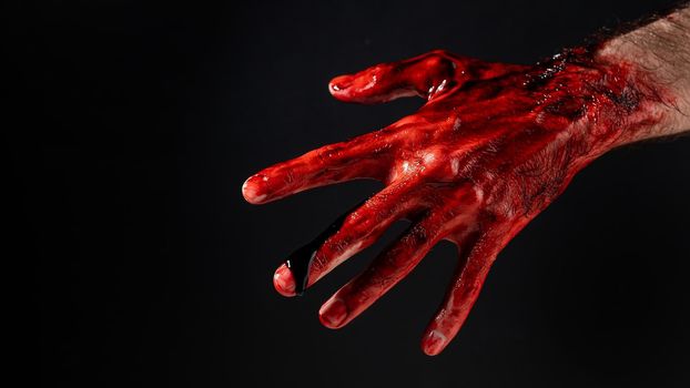 Close-up of a male hand stained with blood on a black background