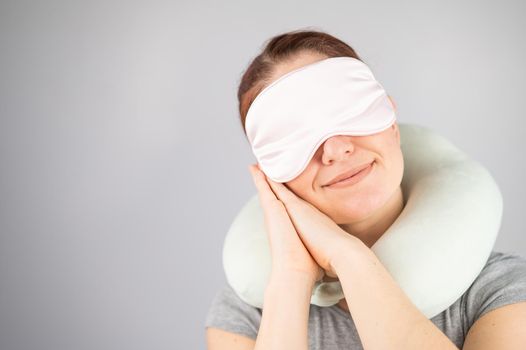 Smiling caucasian woman with travel pillow and sleeping mask isolated on white background