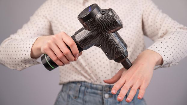 Caucasian business woman massaging her wrist with a percussion massager