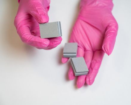 Manicurist in pink gloves holding nail files