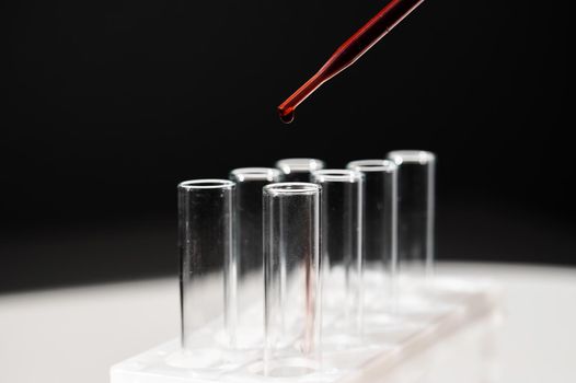 Close-up of a laboratory assistant dripping blood from a pipette into a test tube