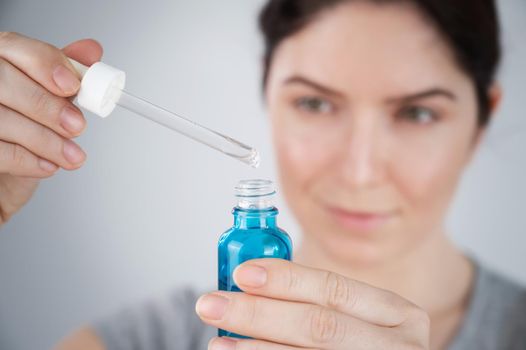 Caucasian woman uses blue anti-wrinkle face serum