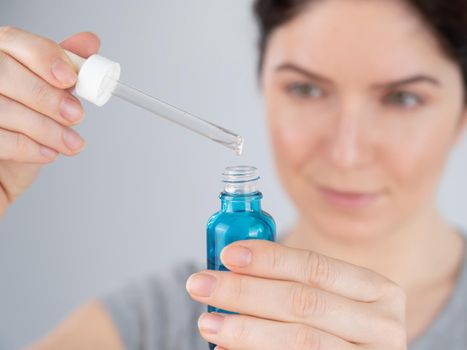 Caucasian woman uses blue anti-wrinkle face serum