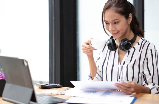 Happy asian woman young wearing headset, communicating with client via video computer call..