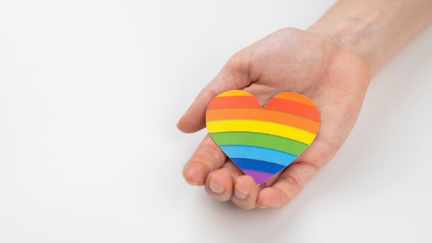 Female hands with rainbow paper heart isolated on white background. Copy space