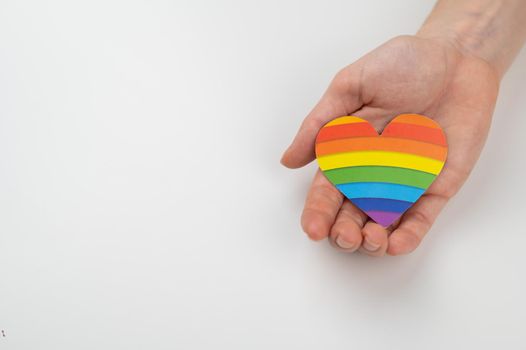 Female hands with rainbow paper heart isolated on white background. Copy space