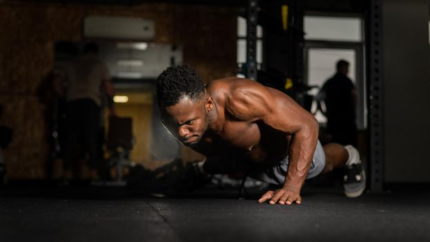 African american man doing one arm push ups in the gym