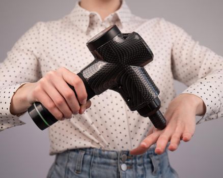 Caucasian business woman massaging her wrist with a percussion massager