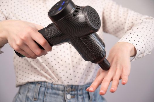 Caucasian business woman massaging her wrist with a percussion massager