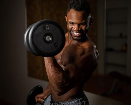 Attractive african american man smiling and doing exercise with dumbbells