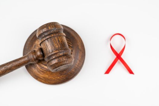 Judicial gavel and red ribbon on a white background. Symbol of the fight against AIDS