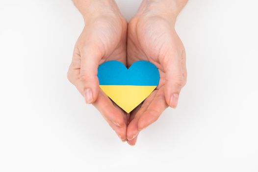 A woman holds a heart with the flag of Ukraine on a white background