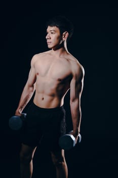 portrait of athletic muscular bodybuilder man with naked torso six pack abs working out with dumbbell. fitness sport exercise concept