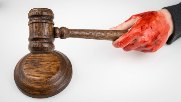 Female judge with bloody hands beats the gavel on a white background