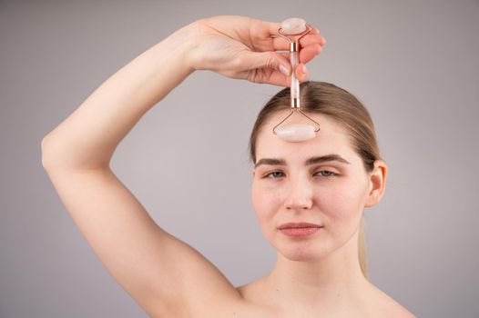 Close-up portrait of a woman uses a quartz roller massager to smooth wrinkles on her forehead