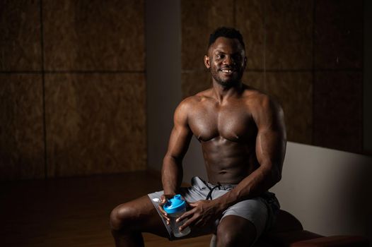 Shirtless african american man drinking from a shaker in the gym