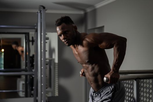 Handsome afro american man doing parallel bars exercise in gym