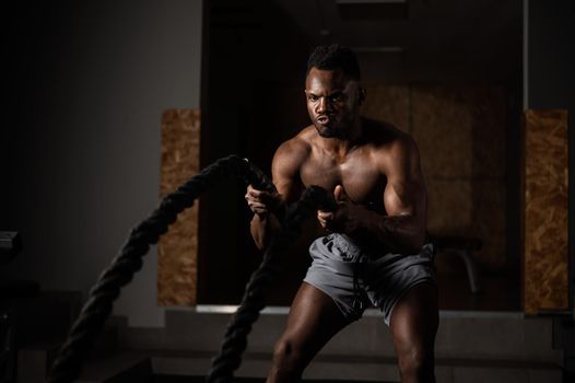 Attractive african american man with naked torso doing endurance exercises with trope