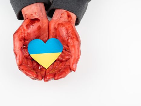 Woman with hands covered in blood holding a heart with the flag of ukraine on a white background