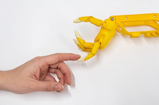 Woman's hand and a plastic hand prosthesis for a child on a white background