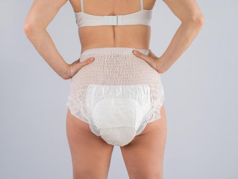 Rear view of a Woman in adult diapers on a white background. Incontinence problem