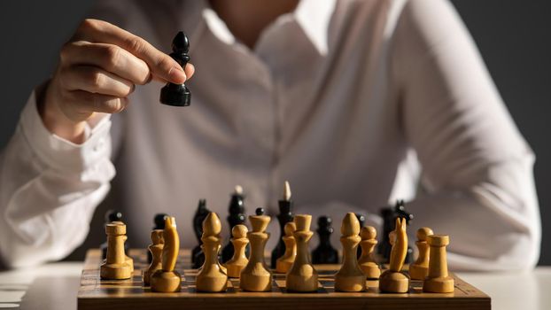 Faceless caucasian woman in white shirt playing chess